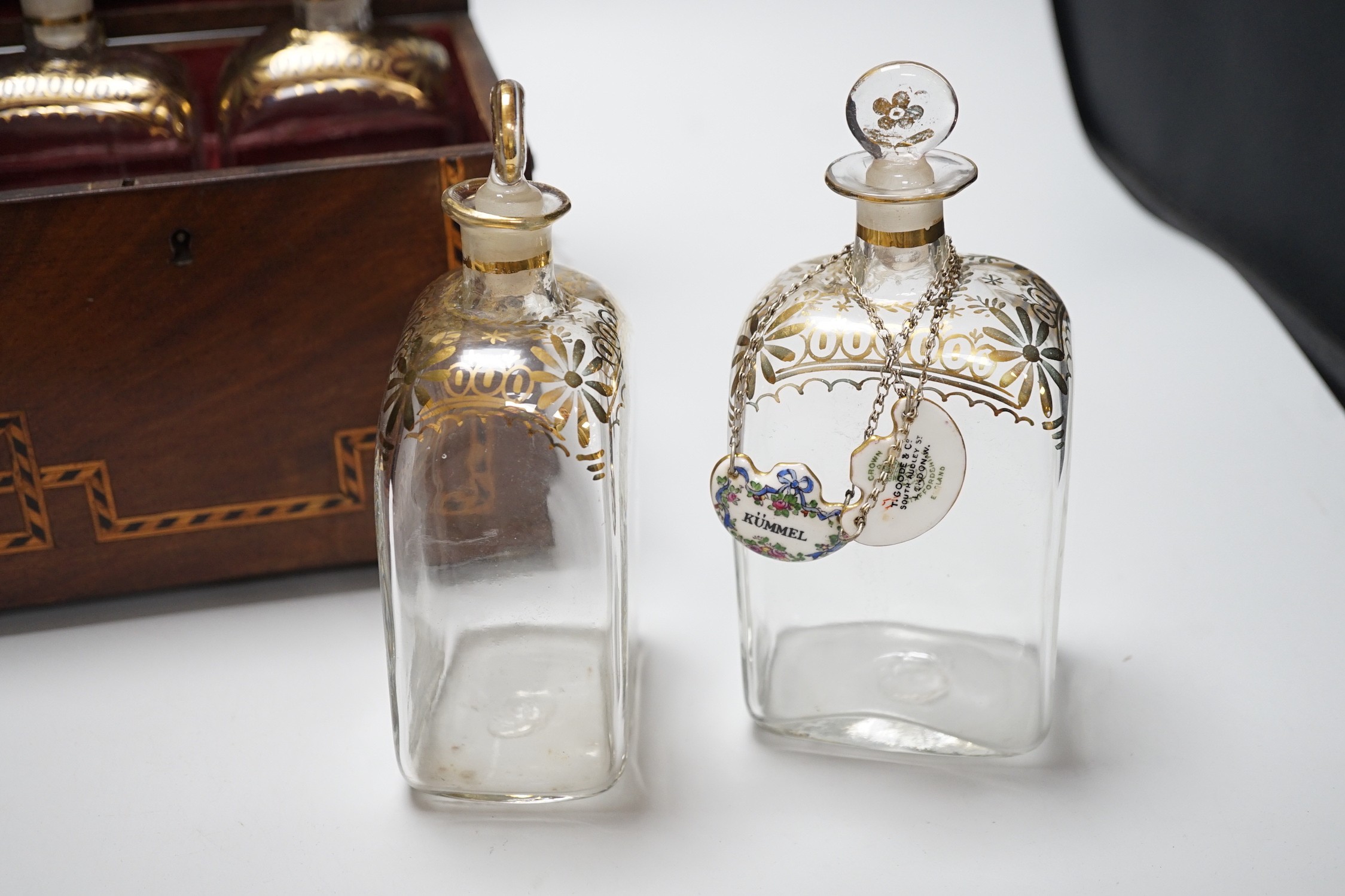 A George III inlaid mahogany decanter set with four gilt decorated decanters and two T.Goode & Co. enamelled wine labels, ‘BRANDY’ and ‘KÜMMEL’. 21cm tall